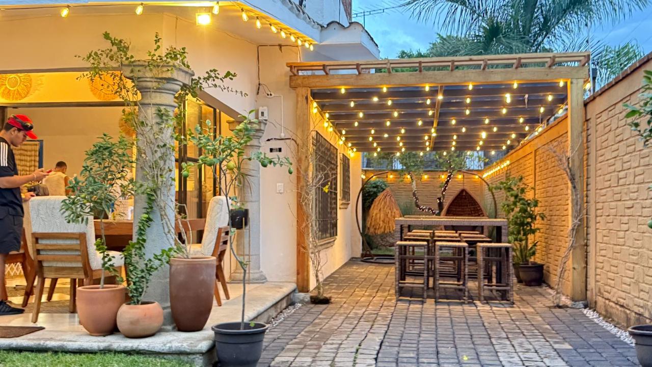 Patio con luces decorativas y pérgola de madera